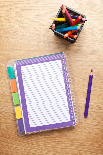 Mesa de escritório com bloco de notas em branco e lápis coloridos