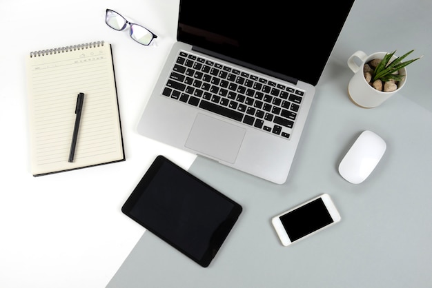 Mesa de escritório com computador portátil, notebook, tablet digital e celular em dois tons b