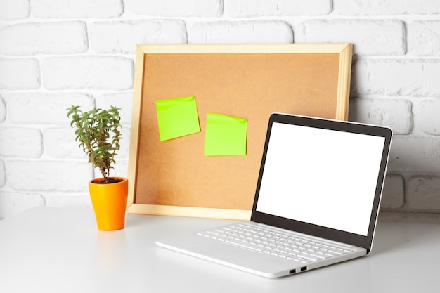 Mesa de escritório com laptop e quadro de avisos nele. Detalhes do negócio interior