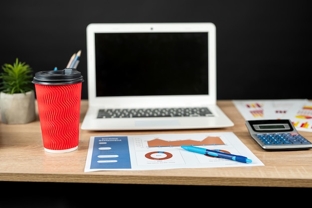 mesa de escritório com laptop papel gráfico de negócios diagrama de rato bloco de notas xícara de café