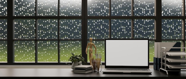 Mesa de escritório com material de escritório para laptop na mesa com gota de chuva na janela ao fundo