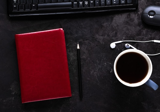 Mesa de escritório com notebook, caneca de café ou chá, teclado, mouse, fones de ouvido e lápis