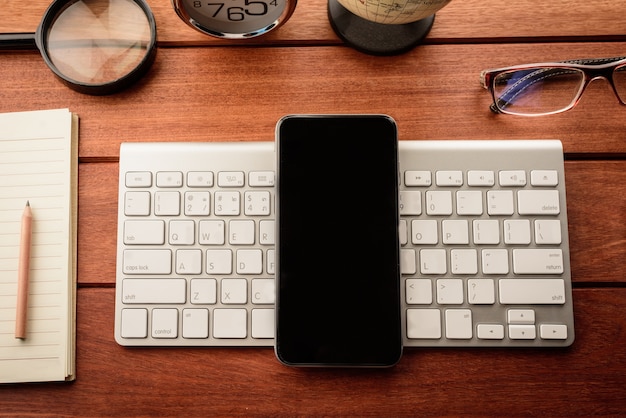 Mesa de escritório com smartphone e suprimentos. Vista do topo.