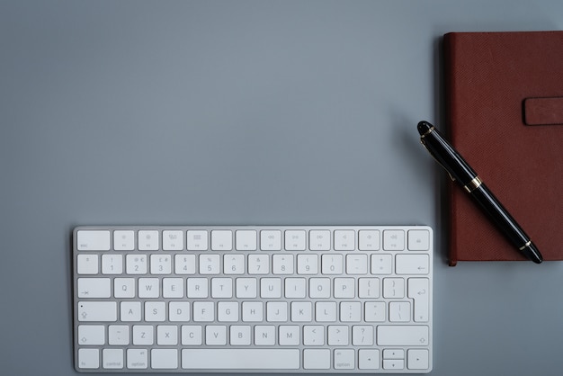 Mesa de escritório com teclado de computador, caderno e caneta de luxo