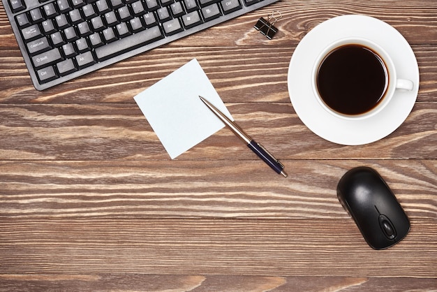 Mesa de escritório com teclado e xícara de café em fundo de madeira