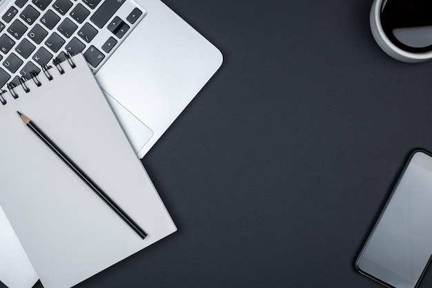 Mesa de escritório de design moderno com página de caderno em branco, computador portátil e xícara de café