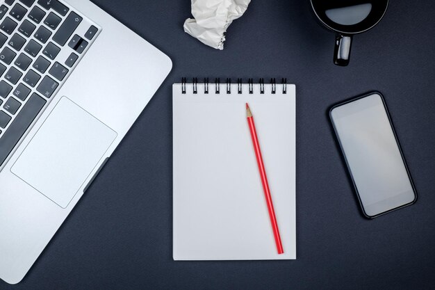 Mesa de escritório de designer moderno com computador portátil de página de caderno em branco e xícara de café