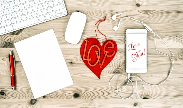Mesa de escritório de dia dos namorados com coração vermelho e telefone móvel. Texto de exemplo Amo você!