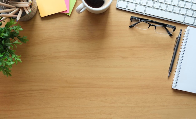 Mesa de escritório de madeira com bloco de notas copos de notas adesivas xícara de café e planta em vaso Vista superior Postura plana com espaço de cópia para o seu texto