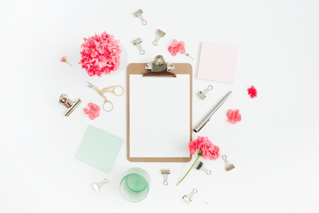 Mesa de escritório em casa plana leigos. Área de transferência com espaço de cópia para texto, flores vermelhas, acessórios, diário de hortelã em branco