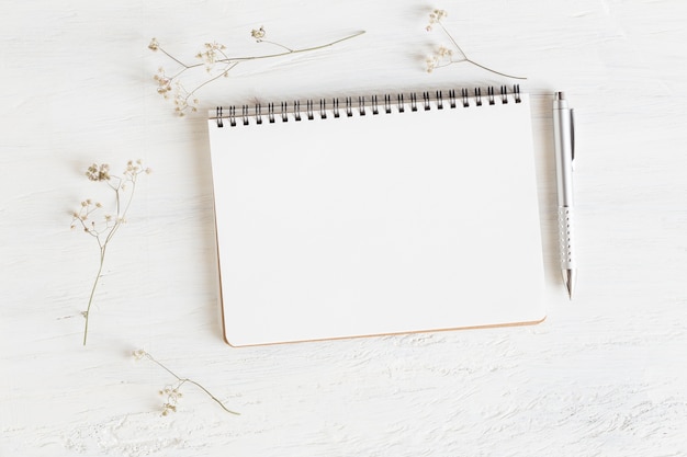 mesa de escritório em fundo branco, caderno vazio aberto na mesa de madeira branca