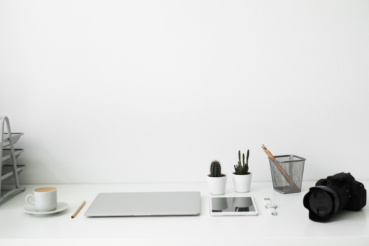 Foto mesa de escritório em que laptop, café, tablet, câmera e outros itens