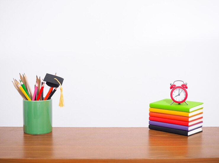 Foto mesa de escritório mesa de trabalho criativa de estudante com papelaria colorida livro de capa dura chapéu de formatura alarme vermelho espaço de cópia para texto de volta às aulas conceito de educação