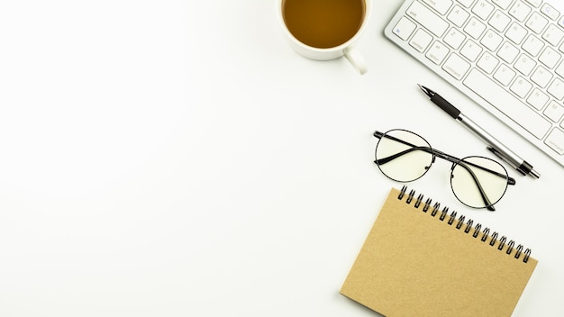 Mesa de escritório moderna branca com um teclado de computador, caneta, caderno e café