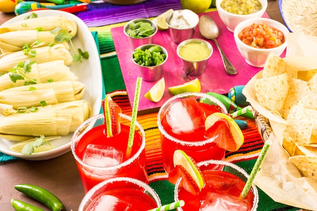 Mesa de festa com tamales, margaritas de morango e pão pan dulche.