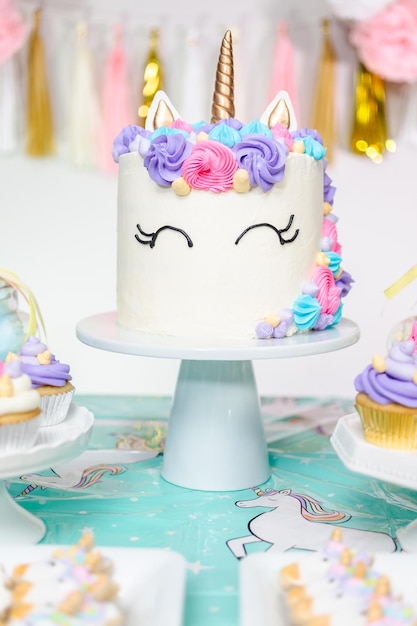 Mesa de festa de aniversário de menina com bolo de unicórnio, cupcakes e biscoitos de açúcar.