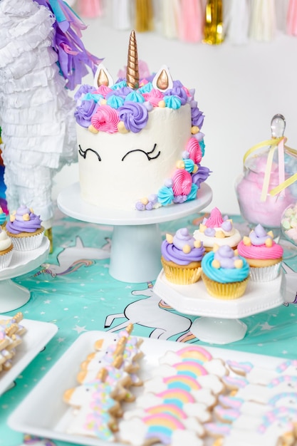 Mesa de festa de aniversário de menina com bolo de unicórnio, cupcakes e biscoitos de açúcar.
