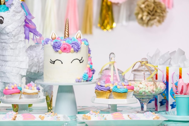 Mesa de festa de aniversário de menina com bolo de unicórnio, cupcakes e biscoitos de açúcar.