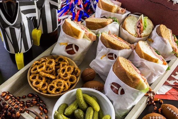 Mesa de futebol para festa de dia de jogo com sanduíche e lanches.