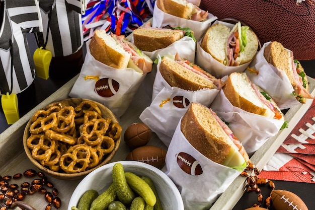 Mesa de futebol para festa de dia de jogo com sanduíche e lanches.