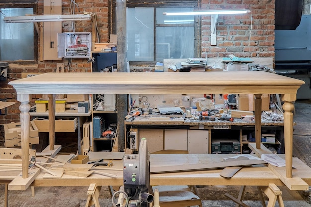 Mesa de jantar de madeira com perna esculpida de carvalho maciço e processo de construção de armação de metal na oficina