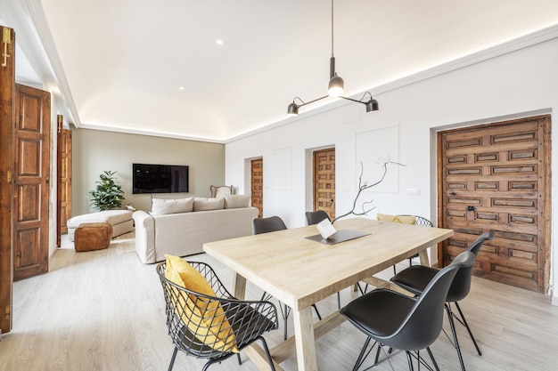 Mesa de jantar em madeira numa sala de estar com sofás e portas de acesso em madeira apainelada