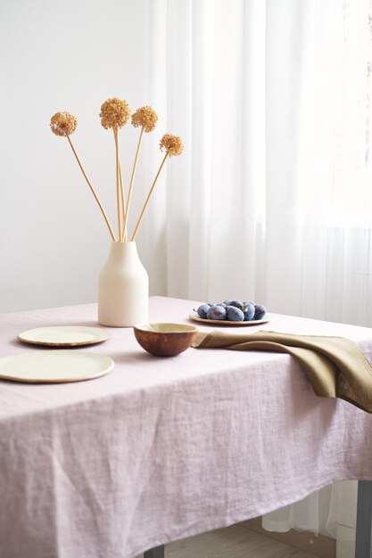 Mesa de jantar moderna com apenas materiais naturais faiança, linho, têxteis, flores secas