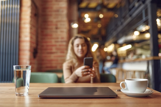 Mesa de madeira com copo d'água, laptop sem fio e xícara de café