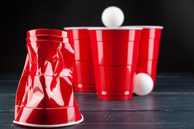 Mesa de madeira com copos vermelhos e bola para pong de cerveja