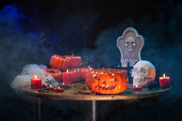 Mesa de madeira com fumaça e decoração de halloween nela. Abóbora esculpida assustador para festa de Hallowee.