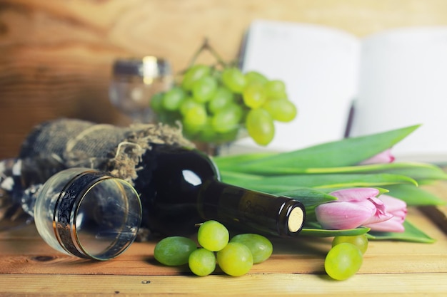 Mesa de madeira com livro de garrafa de vinho e uva