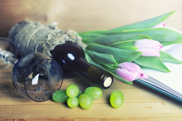 Mesa de madeira com livro de garrafa de vinho e uva