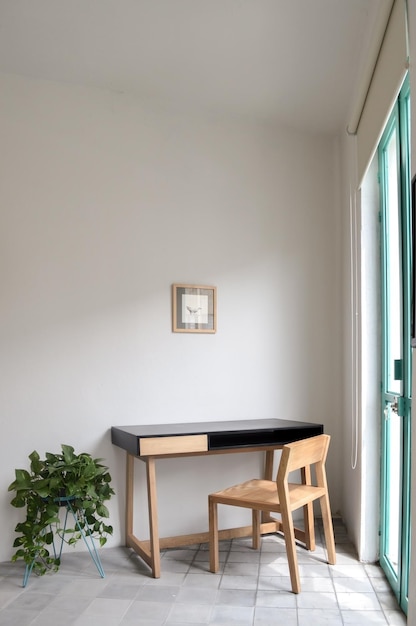 Mesa de madeira com plantas de cadeira na sala luz solar natural entrando em piso de massa, paredes pintadas de branco