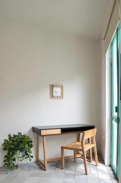 Mesa de madeira com plantas de cadeira na sala luz solar natural entrando em piso de massa, paredes pintadas de branco
