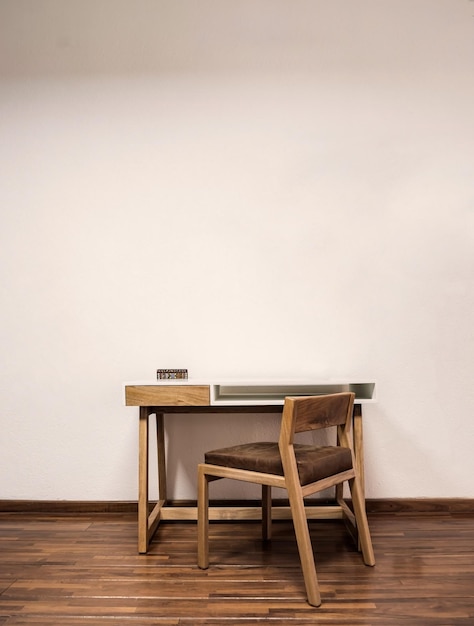 Mesa de madeira com plantas de cadeira na sala luz solar natural entrando em piso de massa, paredes pintadas de branco