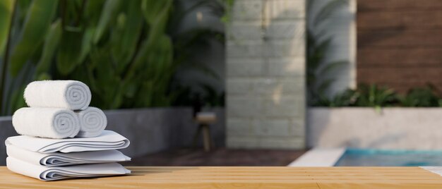 Mesa de madeira com toalhas e espaço de cópia sobre a piscina em casa turva no fundo