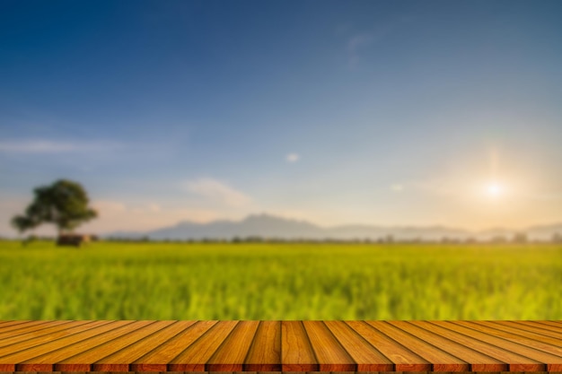 Mesa de madeira e borrão de beleza em um dia de pôr do sol em um campo com céu e montanhas ao fundox