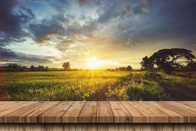 Mesa de madeira e campo de arroz e céu azul por do sol com montagem de exibição de reflexo de lente para produto