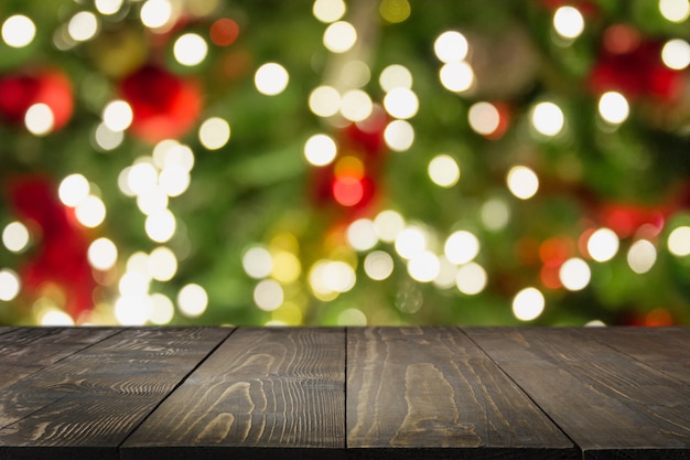 Mesa de madeira escura e bokeh de árvore de Natal turva