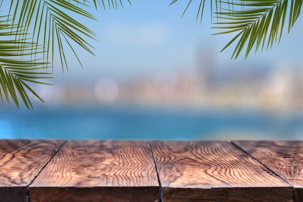 Foto mesa de madeira ou madeira com palmeiras contra o cenário de uma cidade borrada. natural com espaço de cópia.