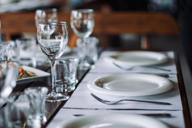 Mesa de madeira servida com pratos garfos colheres copos guardanapos no restaurante