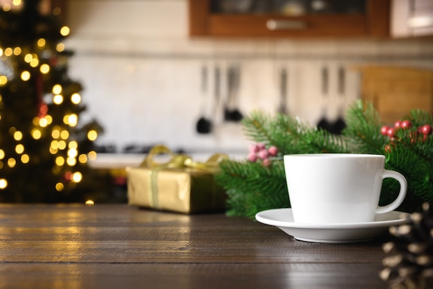 Mesa de madeira vazia com café e cozinha moderna turva com árvore de Natal.