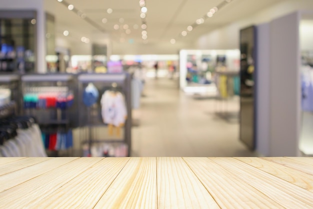 Mesa de madeira vazia com vitrine de loja de roupas elegantes de mulher em shopping center