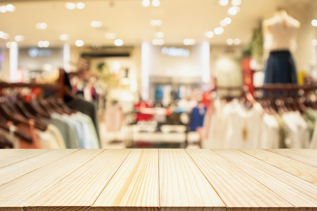 Mesa de madeira vazia com vitrine de loja de roupas femininas elegantes em shopping center