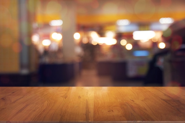 Mesa de madeira vazia em frente ao fundo borrado abstrato da cafeteria. pode ser usado para exibir ou montar seus produtos. Insira a exibição do produto