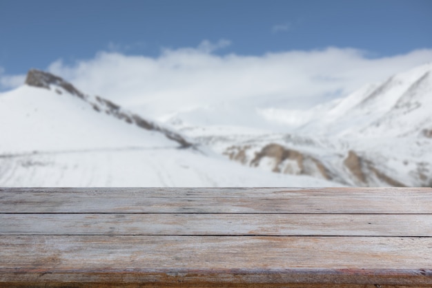 Mesa de madeira velha com pico de neve e fundo de céu azul