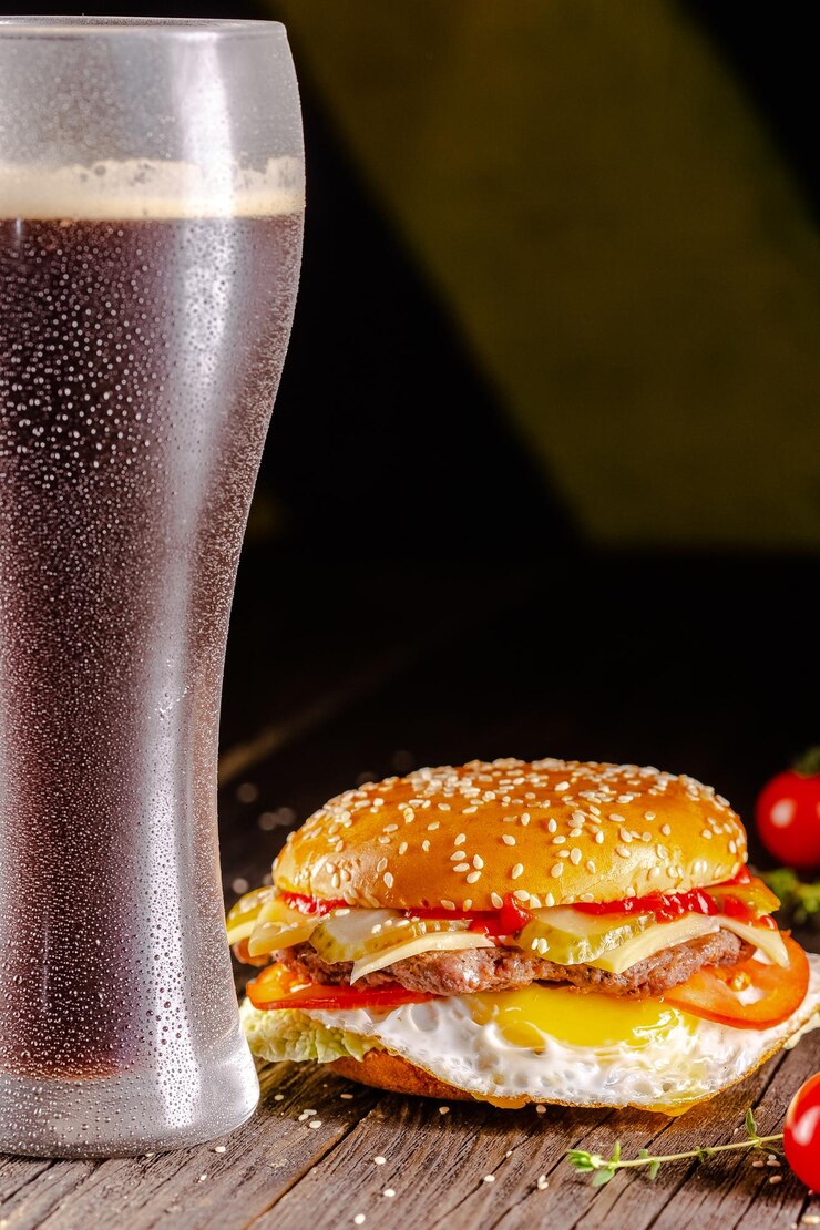Foto mesa de madeira vintage, em uma tábua, pão branco de hambúrguer suculento, queijo, carne de porco fatiada, cerveja i