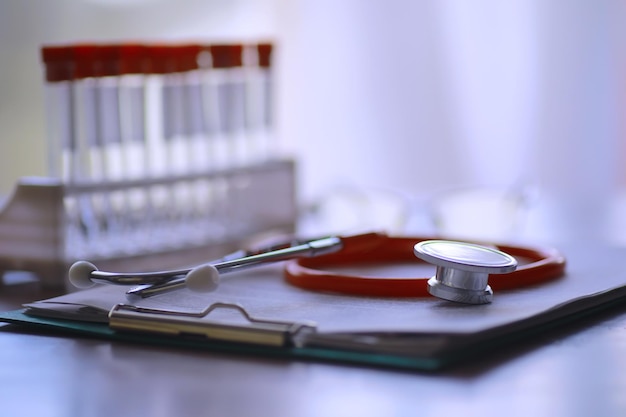 Mesa de médicos no escritório da clínica Tubos de ensaio de estetoscópio prescrições de laptop em cima da mesa