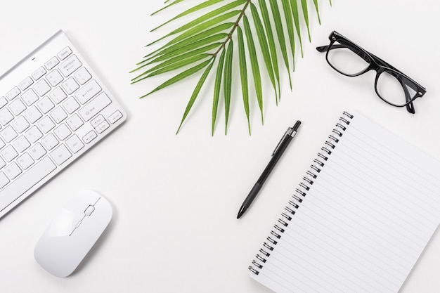 Mesa de mesa de escritório branca com caderno em branco, teclado de computador e outros suprimentos de escritório