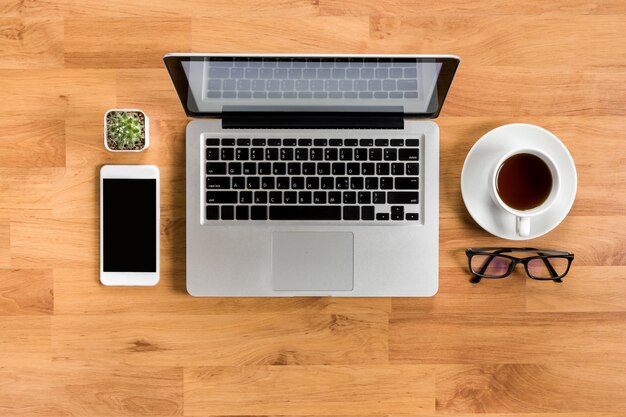 Mesa de mesa de escritório de madeira com laptop, café, smartphone e suprimentos no apartamento leigos.